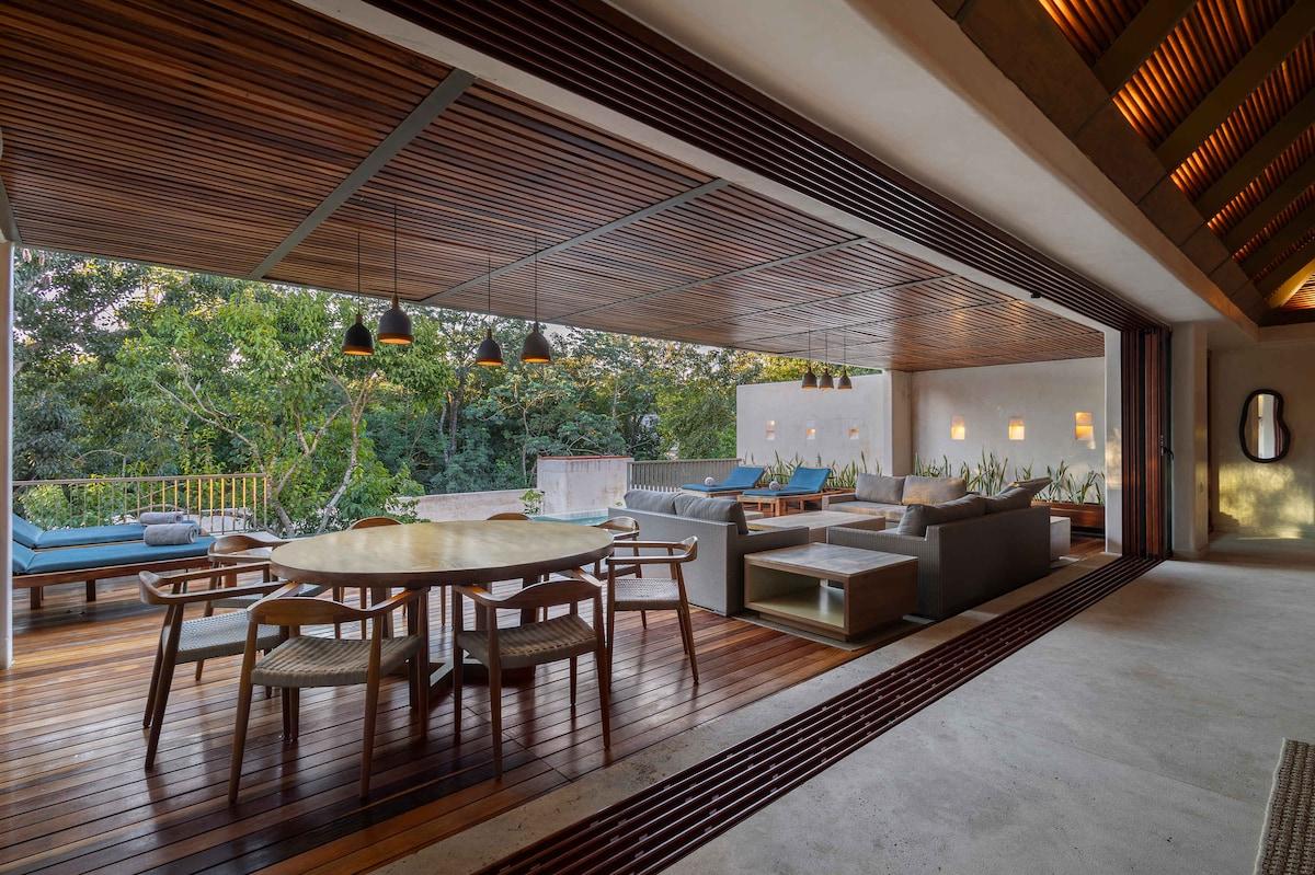 Tropical villa living room with a timber ceiling, pendant lights and a lounge opening to the jungle
