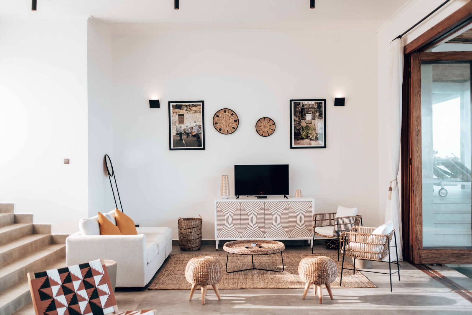 Rattan chairs and pouf in a white vacation-rental living room