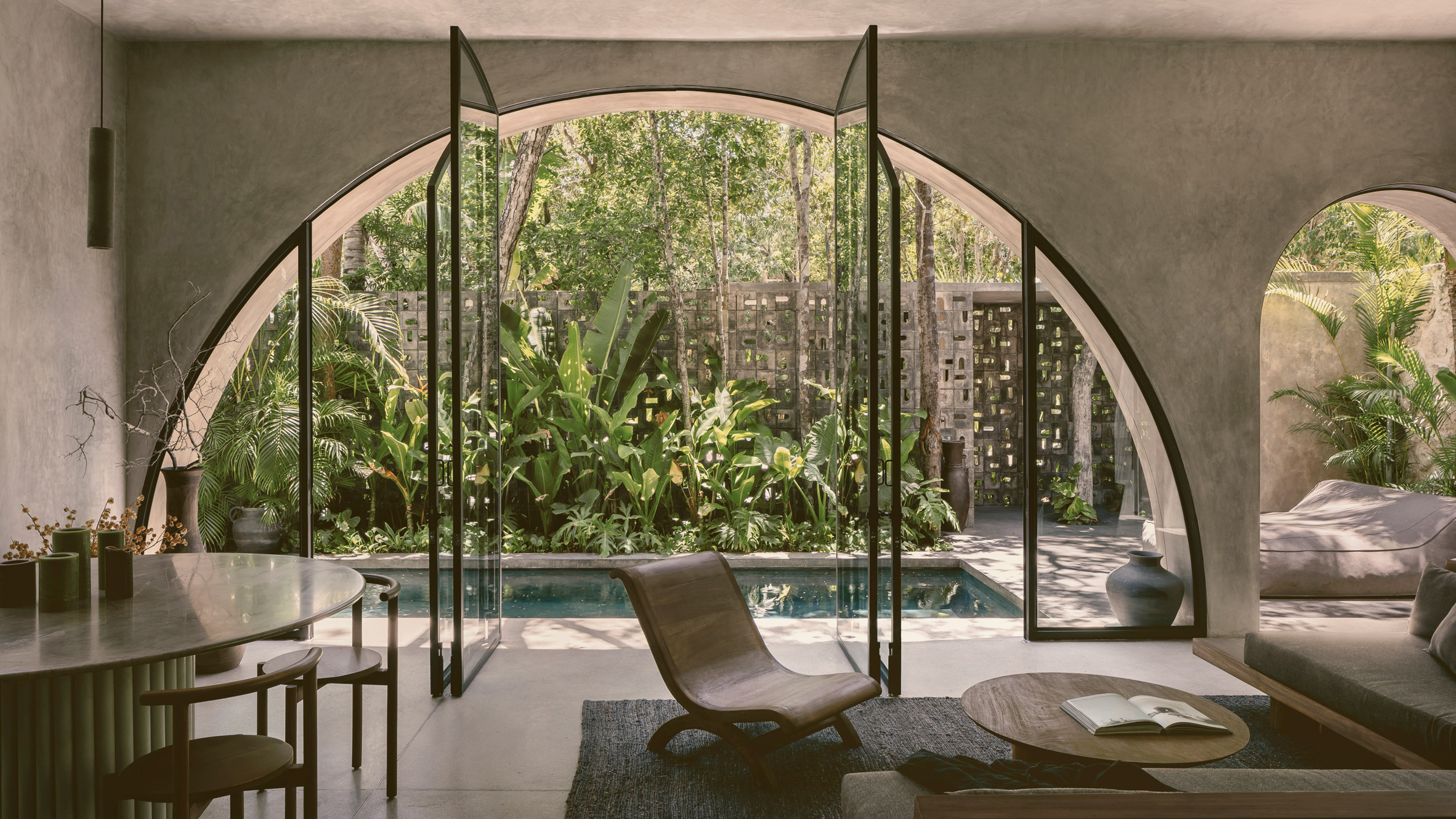 Arched living room opening onto a plunge pool and jungle garden