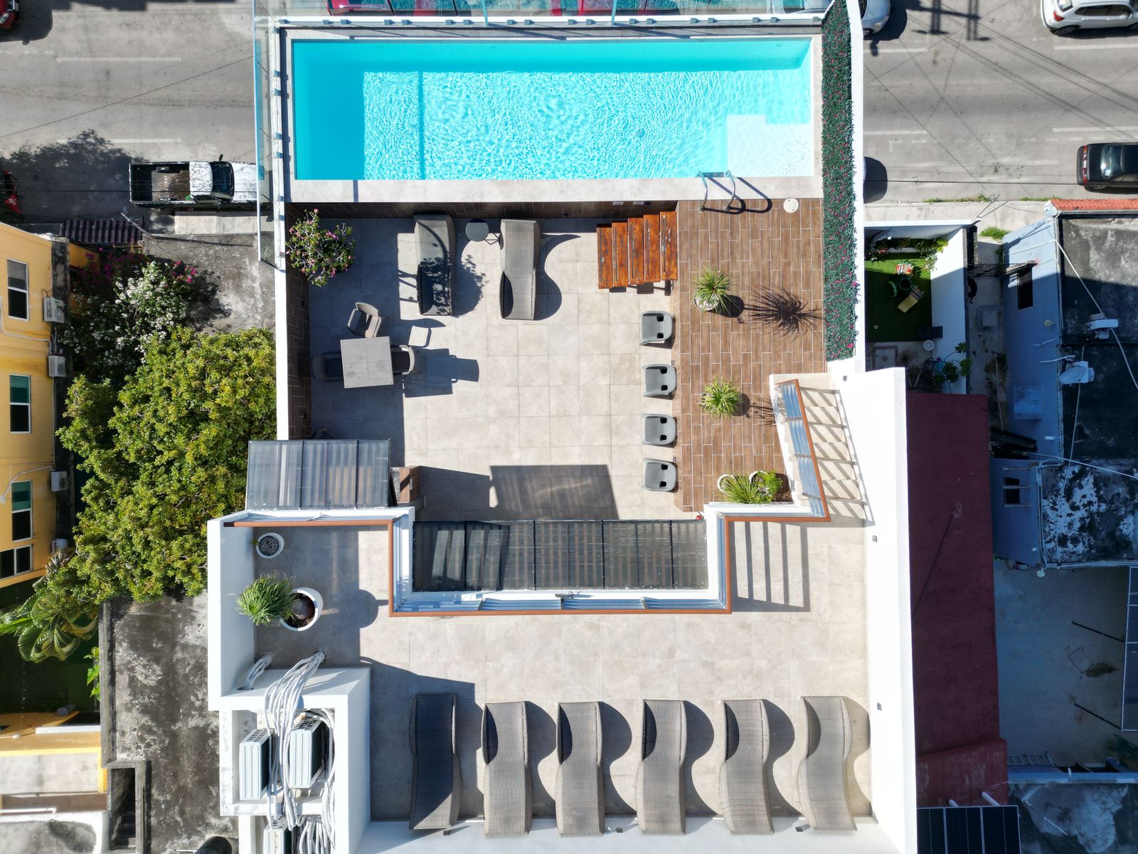Aerial photo of a rooftop terrace with a pool, loungers and a dining area above a city street