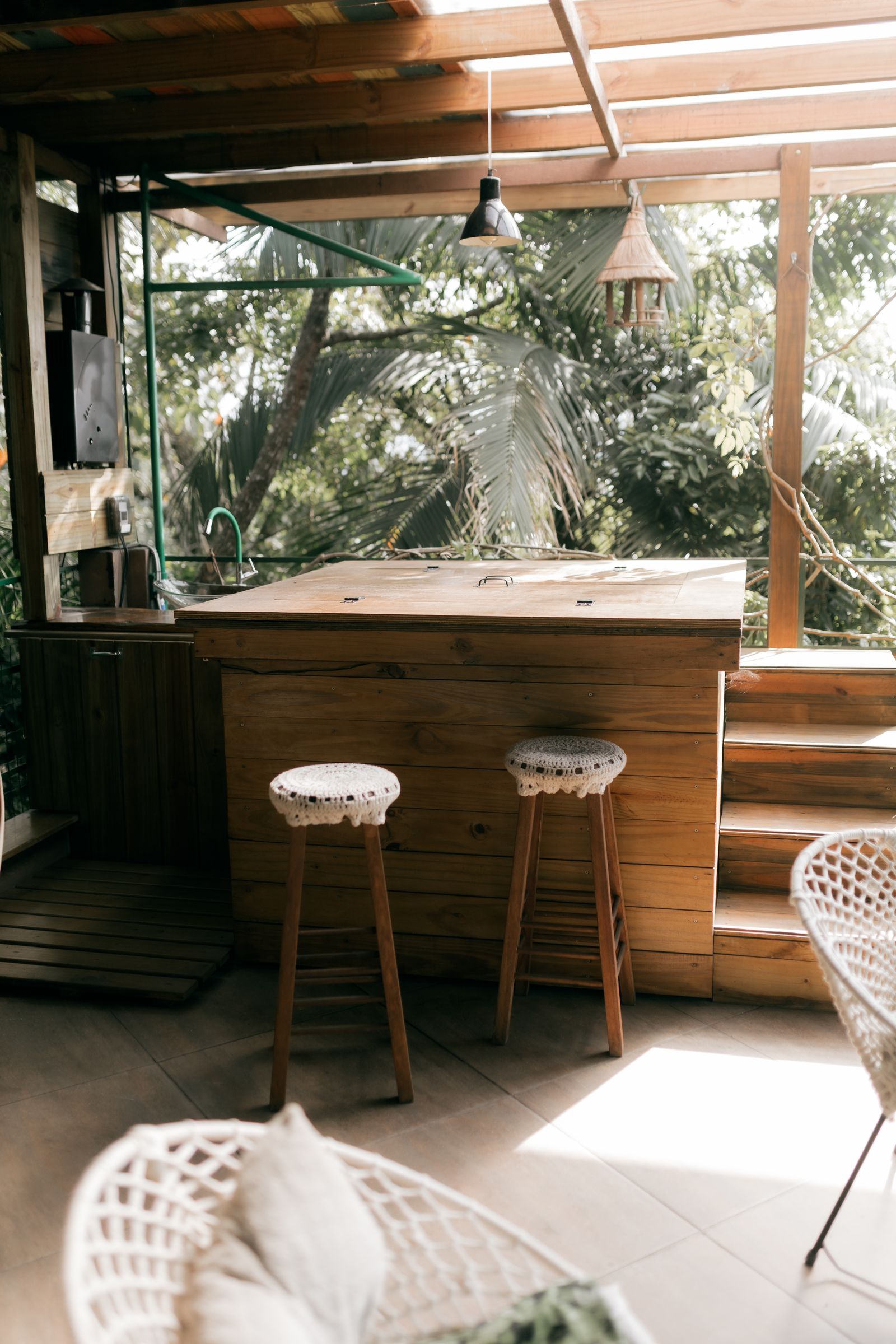 Wood bar counter with stools under a jungle canopy