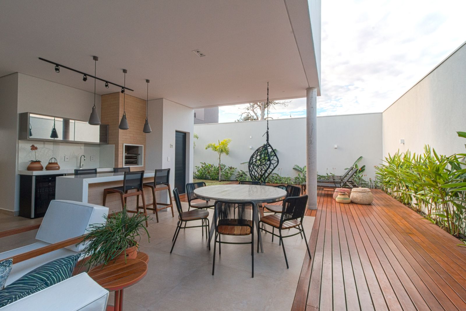 Condo terrace with a built-in outdoor kitchen, a round dining table and a timber deck