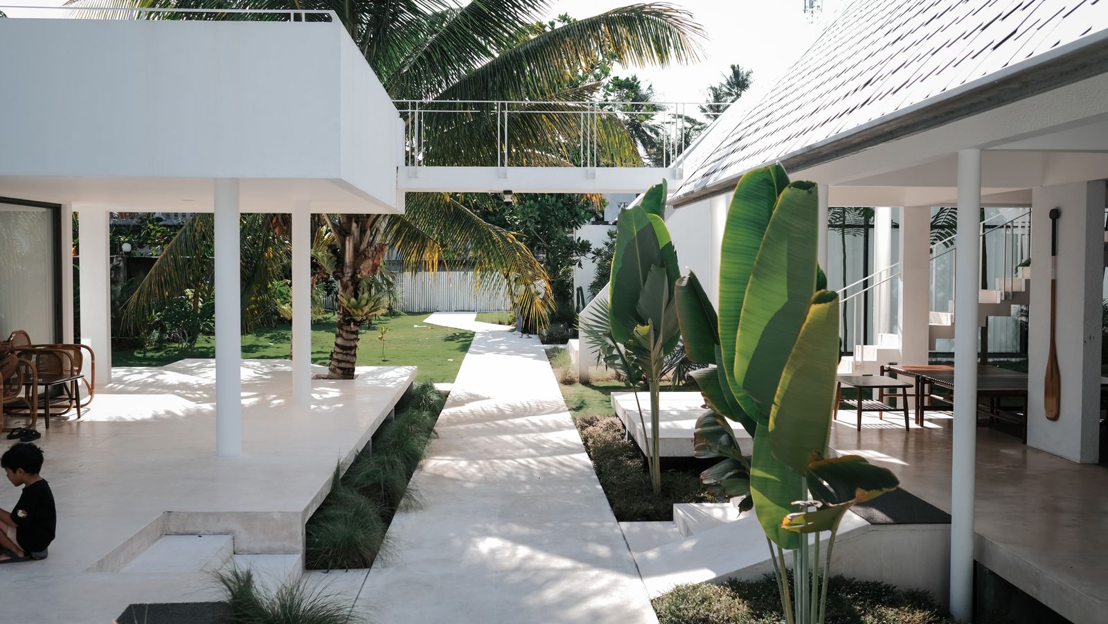 White villa courtyard with a stone path and large tropical plants