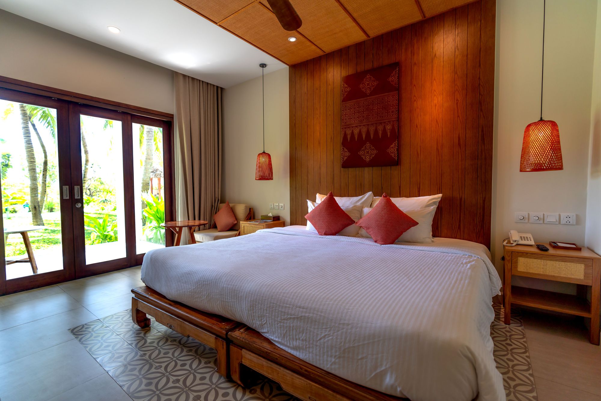 Vacation rental bedroom with warm wood paneling, woven pendant lights and garden doors