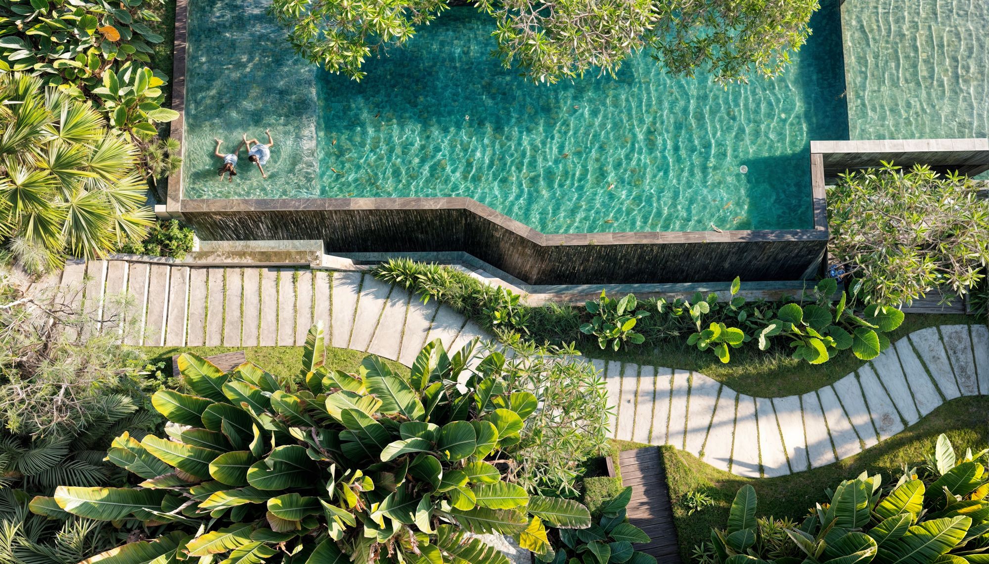 Aerial view of a tropical garden and boardwalk wrapping a pool
