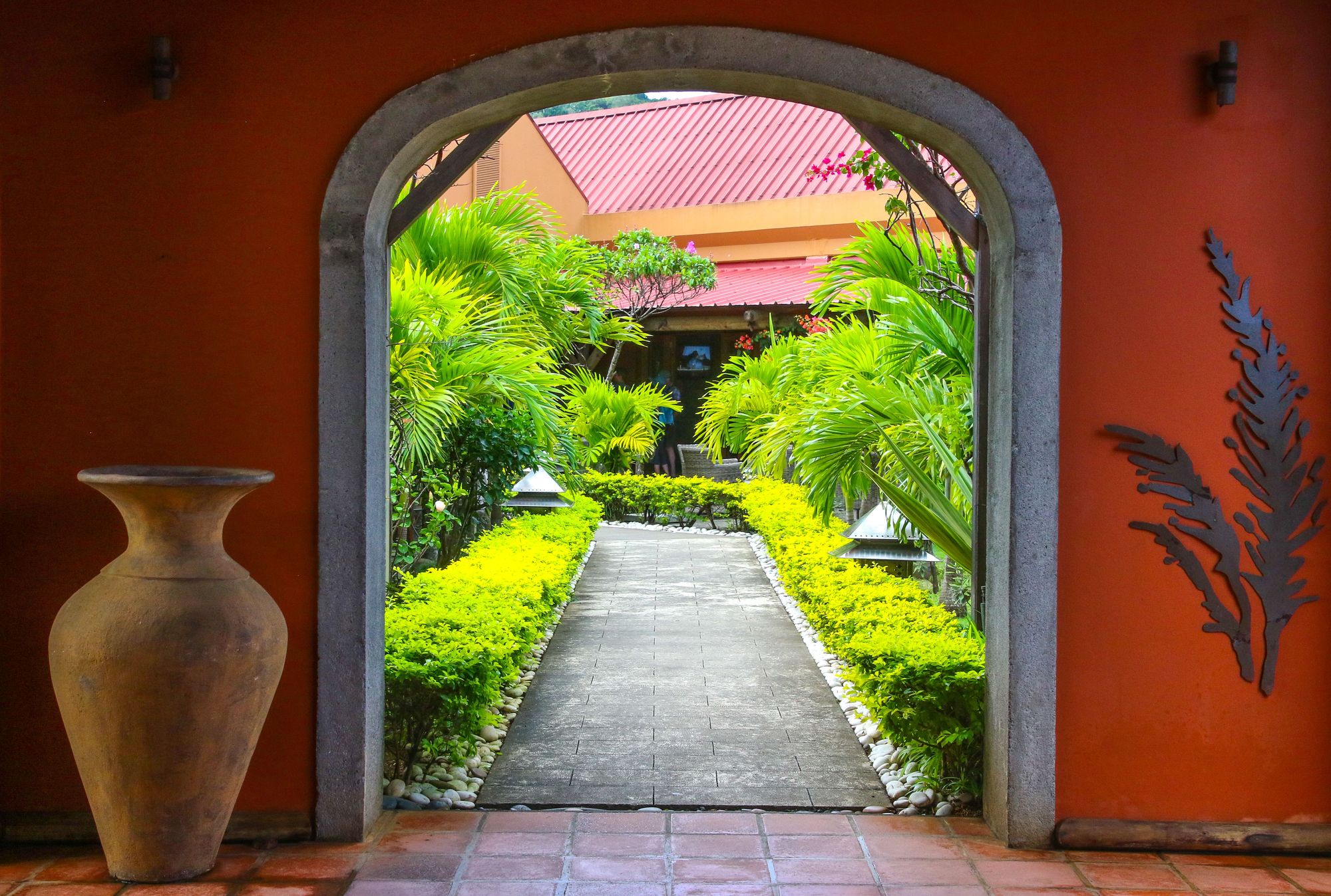 Arched doorway opening onto a hedged tropical garden path