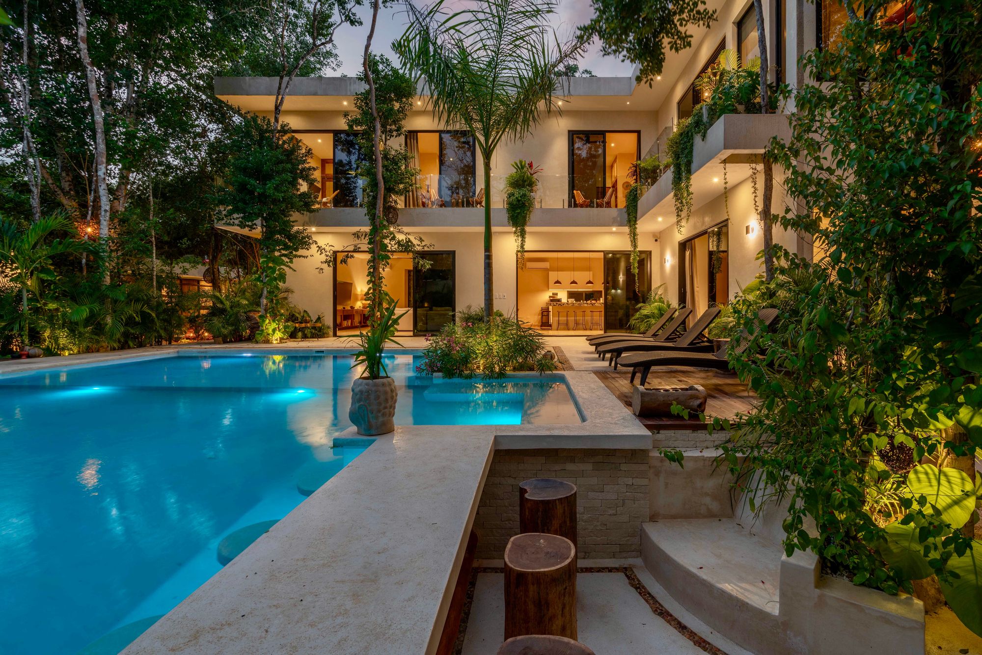 Villa pool and tropical garden lit at dusk
