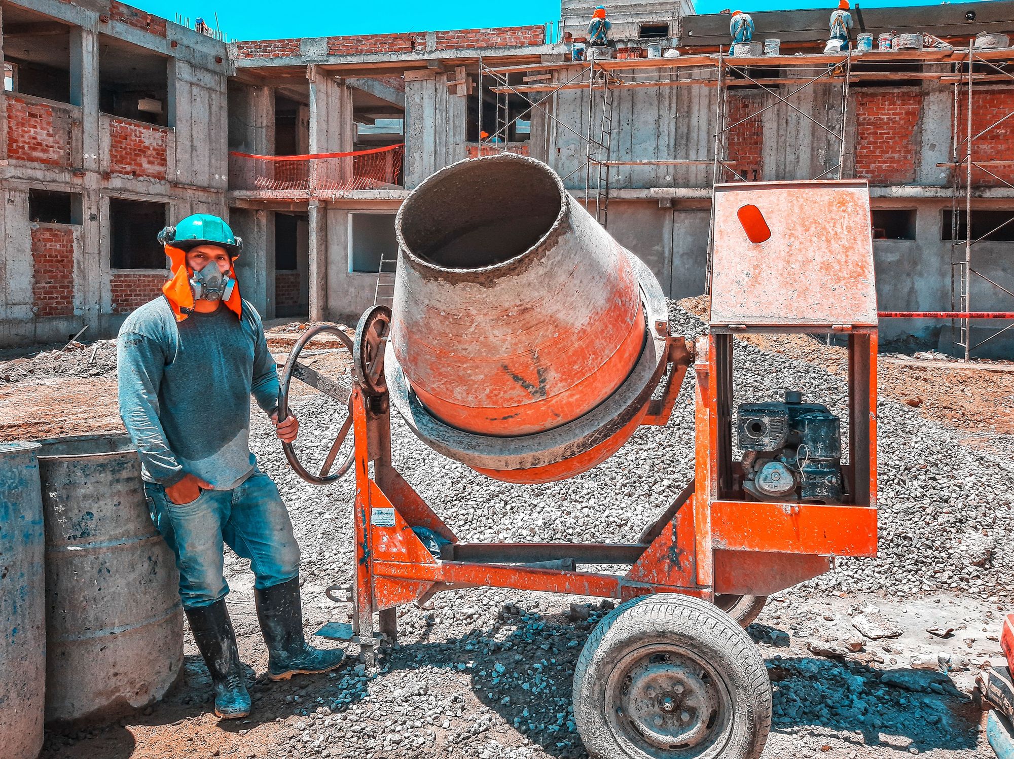Builder beside a cement mixer on an active construction site