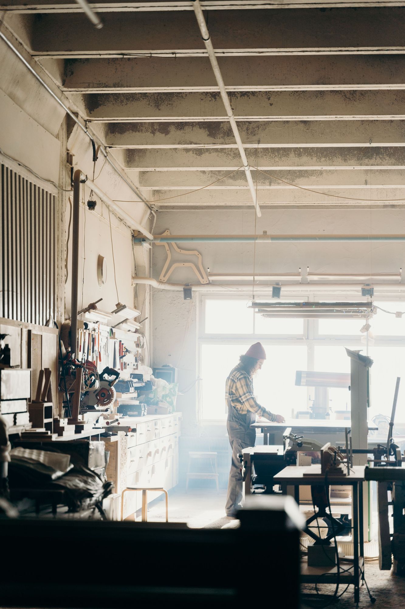 Woodworker at a bench in a light-filled furniture workshop