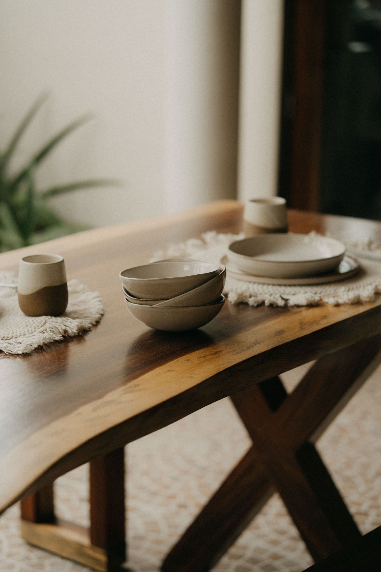 Solid-wood dining table with crossed legs and handmade ceramics