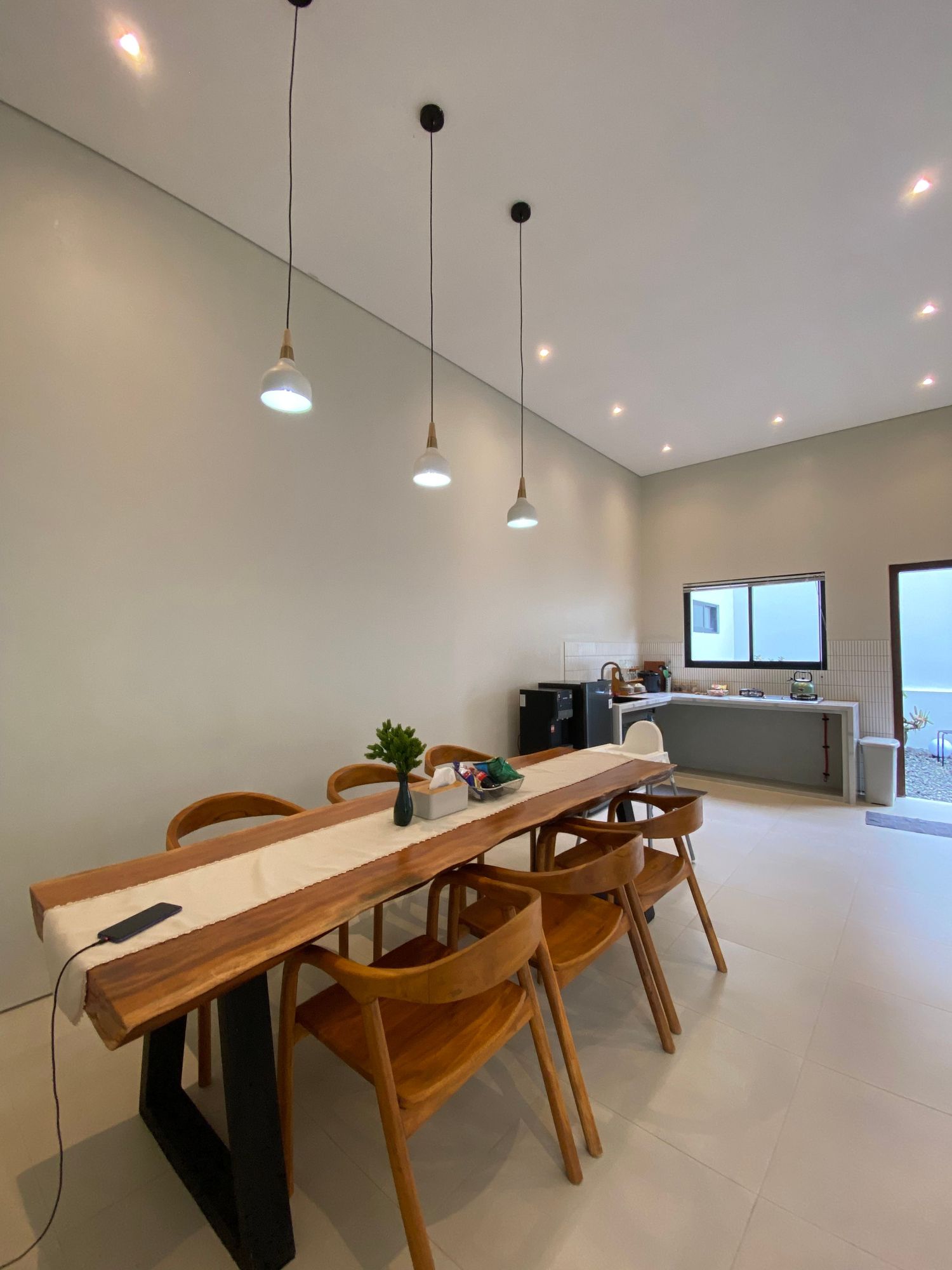 Live-edge dining table under pendant lights in a bright open room