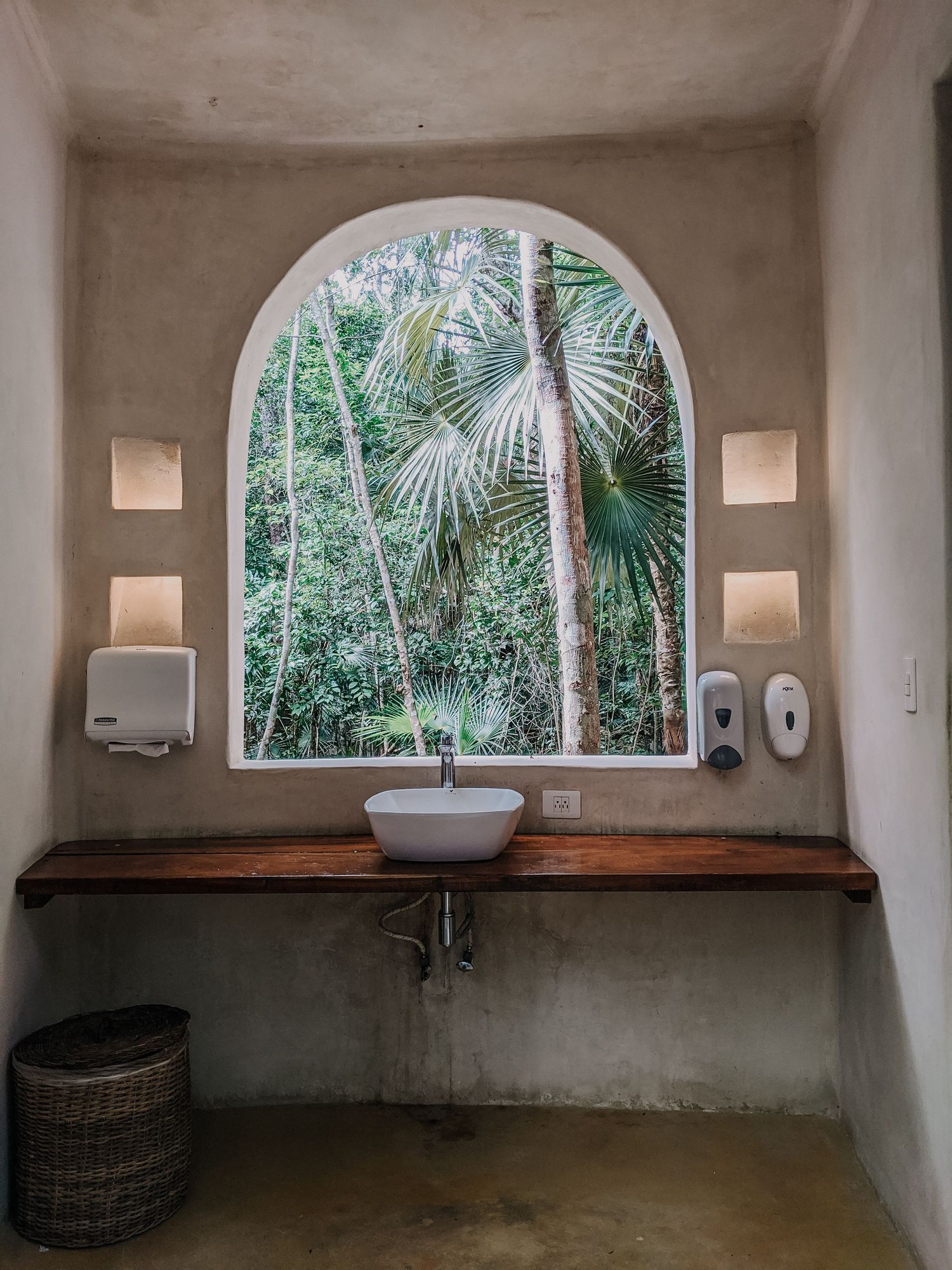 Plaster bathroom with an arched window onto the jungle