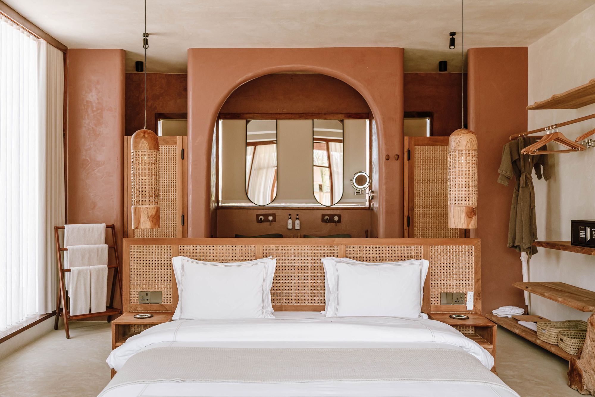 Boutique hotel bedroom with a rattan headboard and terracotta plaster walls