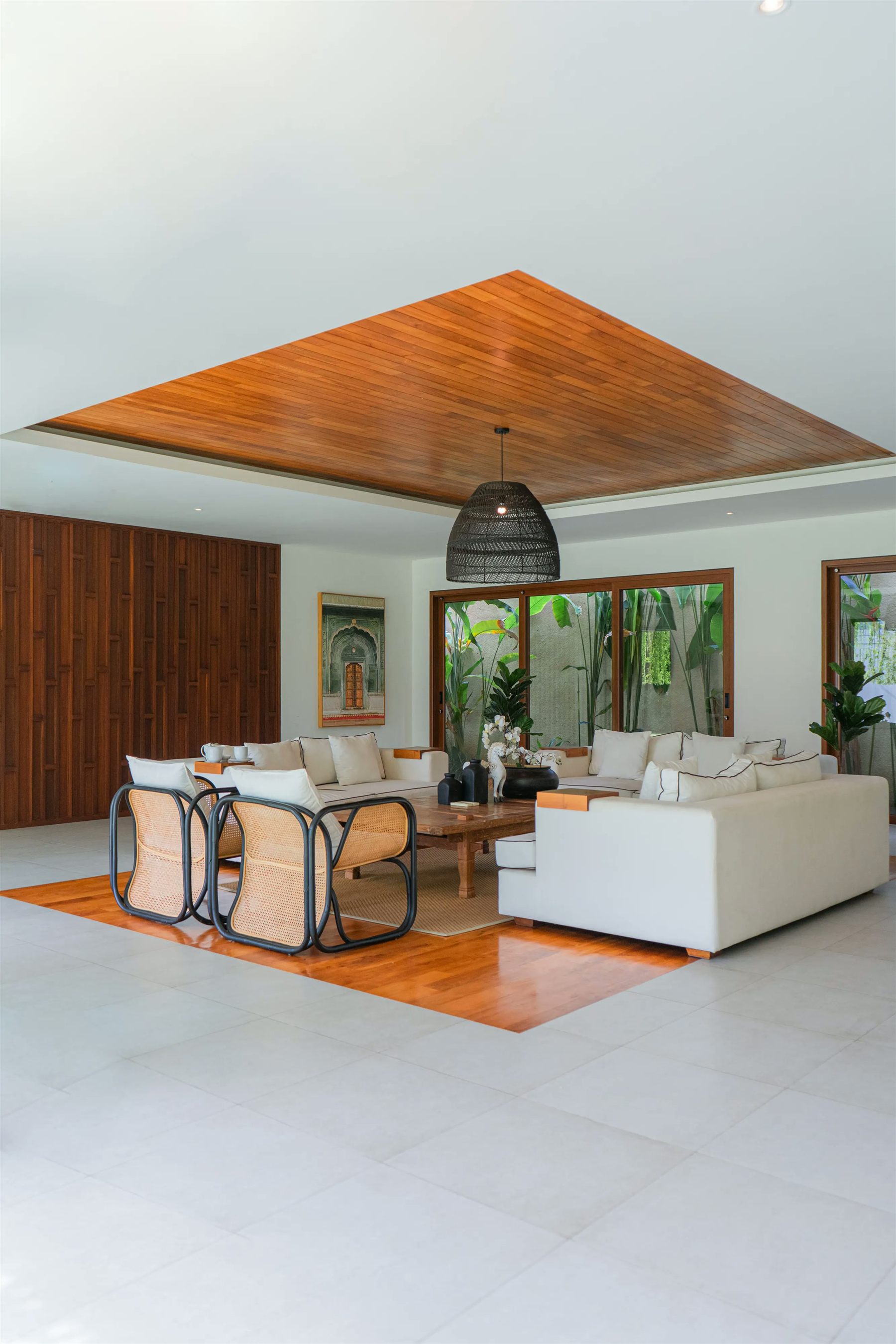 Tropical living room with wood ceiling, linen sofas and rattan